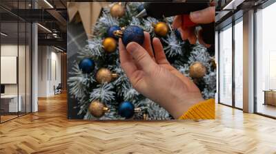 Crafter using hot glue Step by step instruction of making handmade Christmas wreath made of festive decorations in blue and yellow colors. Female hands creating craft homemade decor. New year Wall mural