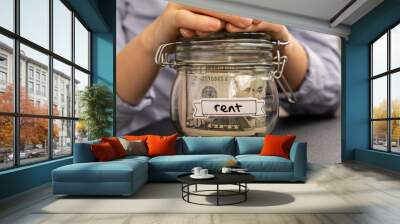 Female hands holding Glass jar full of American currency dollars cash banknote with text RENT. Preparation saving money. Moderate consumption and economy. Collecting money Wall mural