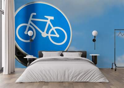 Round road sign depicting white bicycle on blue background, meaning mandatory bike path for cyclists against blue sky background. Blue round sign on bike path pole. Bike path Wall mural