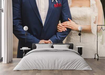 Closeup of a bride holding the groom under his arm, wedding rings on their fingers Wall mural