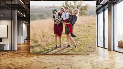 Samesex caucasian lesbian family with a child and a dog walking outdoors on the background of beautiful nature. Mothers having fun with their son. Wall mural