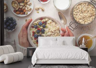 healthy breakfast. Woman eating oatmeal porridge with fresh berry, nuts and honey Wall mural