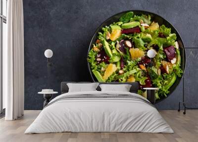 healthy vegan avocado, orange and beet salad in black bowl, dark background Wall mural