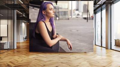 Beautiful brunette woman with colored (purple violet blue) hair in dark black slim dress outdoor in the european city, smiling Wall mural