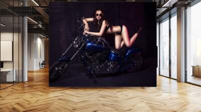 Brunette sexy woman in black underwear, heels and sunglasses in studio in red light on a motorcycle. Indoors Wall mural