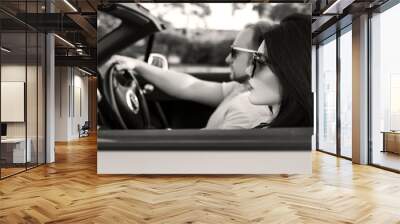 Gorgeous sexy copule of man and woman on a vacation car trip in summer day. Luxury grey sport car. Sexy fit brunette woman and man in casual outfit. Sunset Wall mural