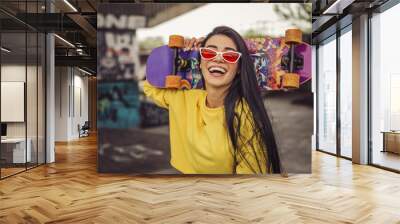 Sexy slim fit brunette woman in sport casual outfit in a skate park. Active leisure on a longboard Wall mural