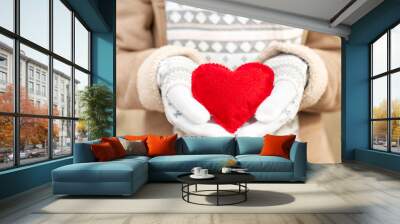 Girl hands in white knitted mittens holding romantic red heart Wall mural