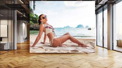 Young pretty slim brunette woman in sunglasses getting suntan on tropical beach Wall mural