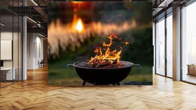 black grill with fire isolated on sunset lake background, camping weekends in nature, summer leisure time, relax and eat time Wall mural