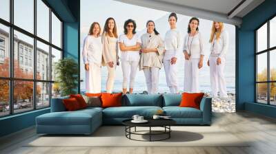 Group portrait of beautiful women posing outside with beautiful mountain landscape on background, wearing white clothes Wall mural