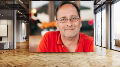 Outdoor portrait of 50 year old man wearing red polo shirt and eyeglasses Wall mural