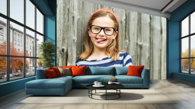 Outdoor portrait of a cute little 9 year old girl wearing eyeglasses Wall mural