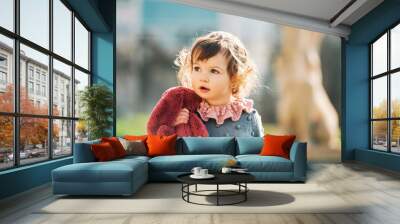 Outdoor portrait of adorable toddler girl playing wirh pink bunny toy Wall mural