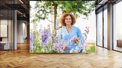 Outdoor portrait of beautiful 50 year old woman enjoying nice day in flower park or garden, happy and healthy lifestyle Wall mural