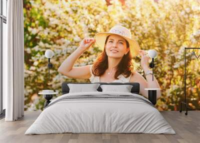 Outdoor portrait of beautiful mature woman in spring park enjoying blossoming of Jasmine flowers Wall mural