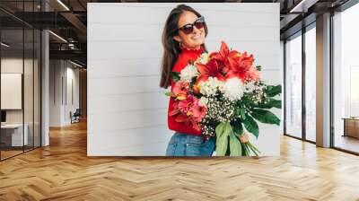 Outdoor portrait of beautiful young woman holding big bouquet with a variety of flowers Wall mural