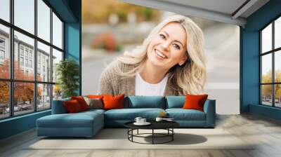 Outdoor portrait of happy smiling woman with blonde hair Wall mural