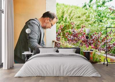 Portrait of middle age man planting seedlings on the balcony, small cozy garden in apartment Wall mural