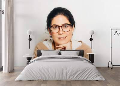 Studio portrait of beautiful brunette woman, wearing glasses, leaning on a hand, posing on white background Wall mural