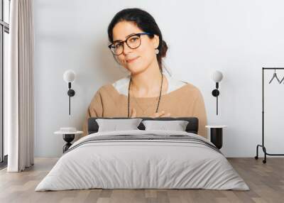 Studio portrait of beautiful brunette woman, wearing glasses, showing thank you gesture, posing on white background Wall mural