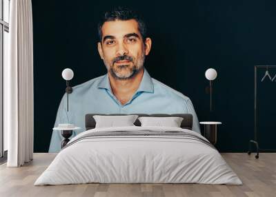 Studio portrait of handsome man wearing formal blue shirt, posing on black background Wall mural