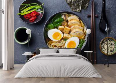 Asian noodle soup, ramen with chicken, tofu, vegetables and egg in black bowl. Slate background. Top view. Wall mural