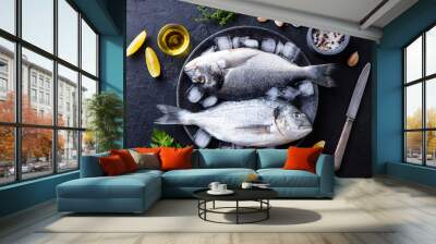 Dorado raw fish on a plate with ice and lemon. Black slate background. Top view. Wall mural