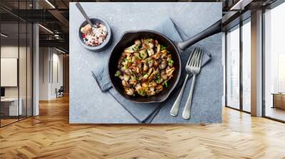 Fried mushrooms with fresh herbs in black cast iron pan. Top view. Wall mural