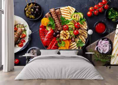 Grilled meat kebabs, vegetables on a black plate with tortillas, flat bread. Slate background. Top view. Wall mural