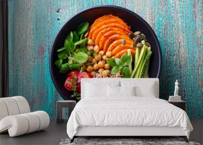 Healthy vegetarian salad. Roasted pumpkin, quinoa, tomatoes, green salad. Buddha bowl. Blue wooden background. Top view. Wall mural