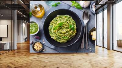 Pasta spaghetti with pesto sauce and fresh basil leaves in black bowl. Grey background. Top view. Wall mural