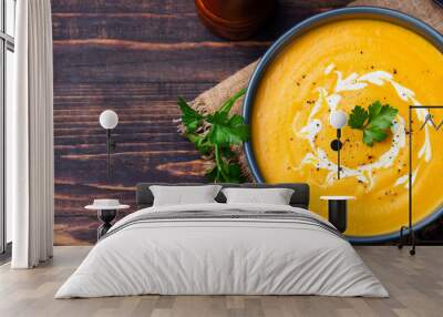 Pumpkin and carrot soup with cream and parsley on dark wooden background Top view Copy space Wall mural