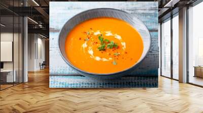 Pumpkin soup with fresh herbs in a bowl. Blue wooden background. Close up. Wall mural