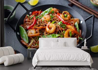 Stir fry noodles with vegetables and shrimps in black iron pan. Dark background. Close up. Wall mural