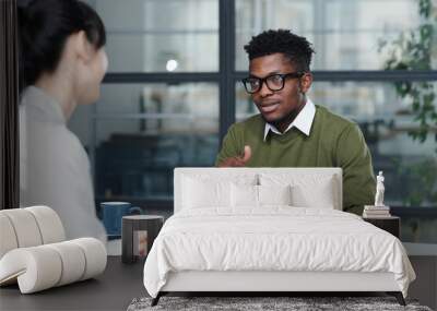 African American businessman discussing resume with candidate during their meeting in office Wall mural