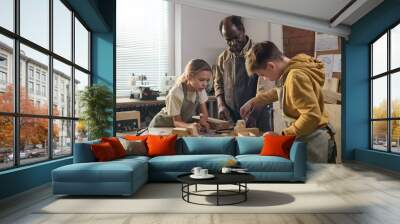 African American craftsman with two children building wooden toys together in carpenting workshop Wall mural