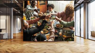 African big family toasting with glasses with lemonade while having holiday dinner together at table at home Wall mural