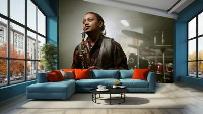 Medium shot of African American male jazz musician holding saxophone standing on stage, copy space Wall mural