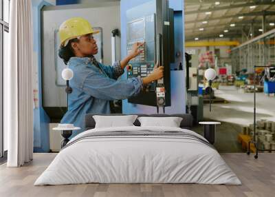 Medium shot of young African American woman working in factory adjusting settings on CNC machine, copy space Wall mural