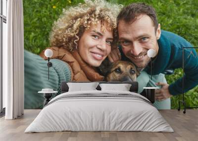 Portrait of young couple with dog smiling at camera while walking on the nature Wall mural