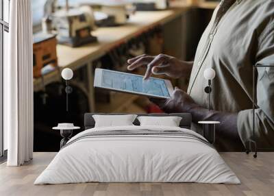 Side view closeup of carpenter holding digital tablet in workshop with woodworking plans on screen Wall mural