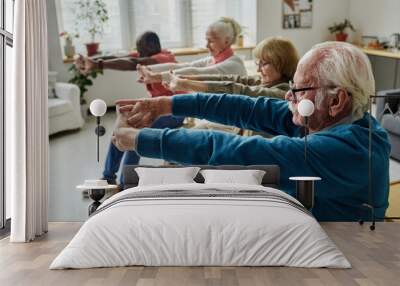 Side view of senior people doing exercises sitting on chairs in the morning in the room Wall mural