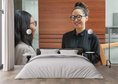 Smiling young businesswoman talking to her colleague at office Wall mural