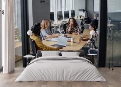 Three multi-ethnic women and indian man in wheelchair having business meeting at desk in office Wall mural