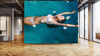 Beautiful female in swimming pool background with white Spa flowers Wall mural