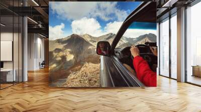 Driver in car on the edge of cliff in wild mountains Wall mural