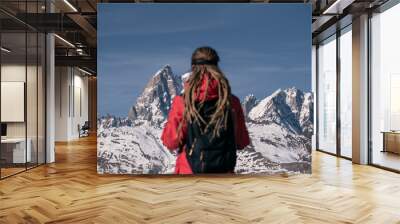 Silhouette of young woman out of focus with long dreadlocks and backpack against background of winter mountain peaks covered with snow Wall mural