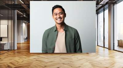 medium shot portrait of a happy Filipino man in his 30s wearing a chic cardigan against a minimalist or empty room background Wall mural