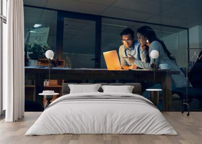 Making important decisions together to improve their chances at success. Cropped shot of two colleagues working late on a laptop in an office. Wall mural